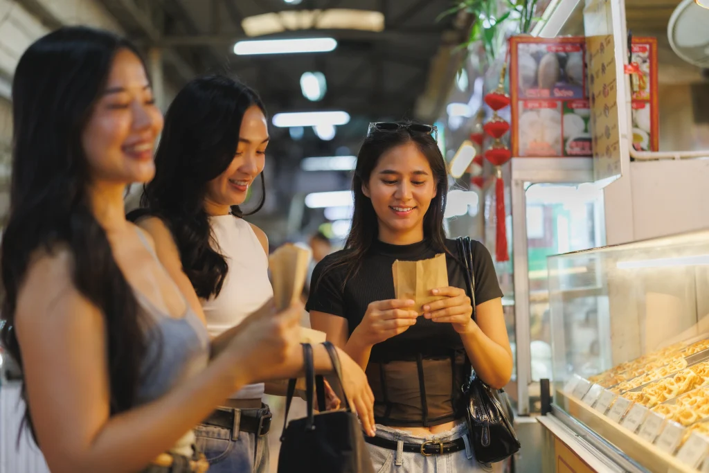 Young, happy group of women on a tour, trying local hawker centre food