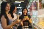 Young, happy group of women on a tour, trying local hawker centre food